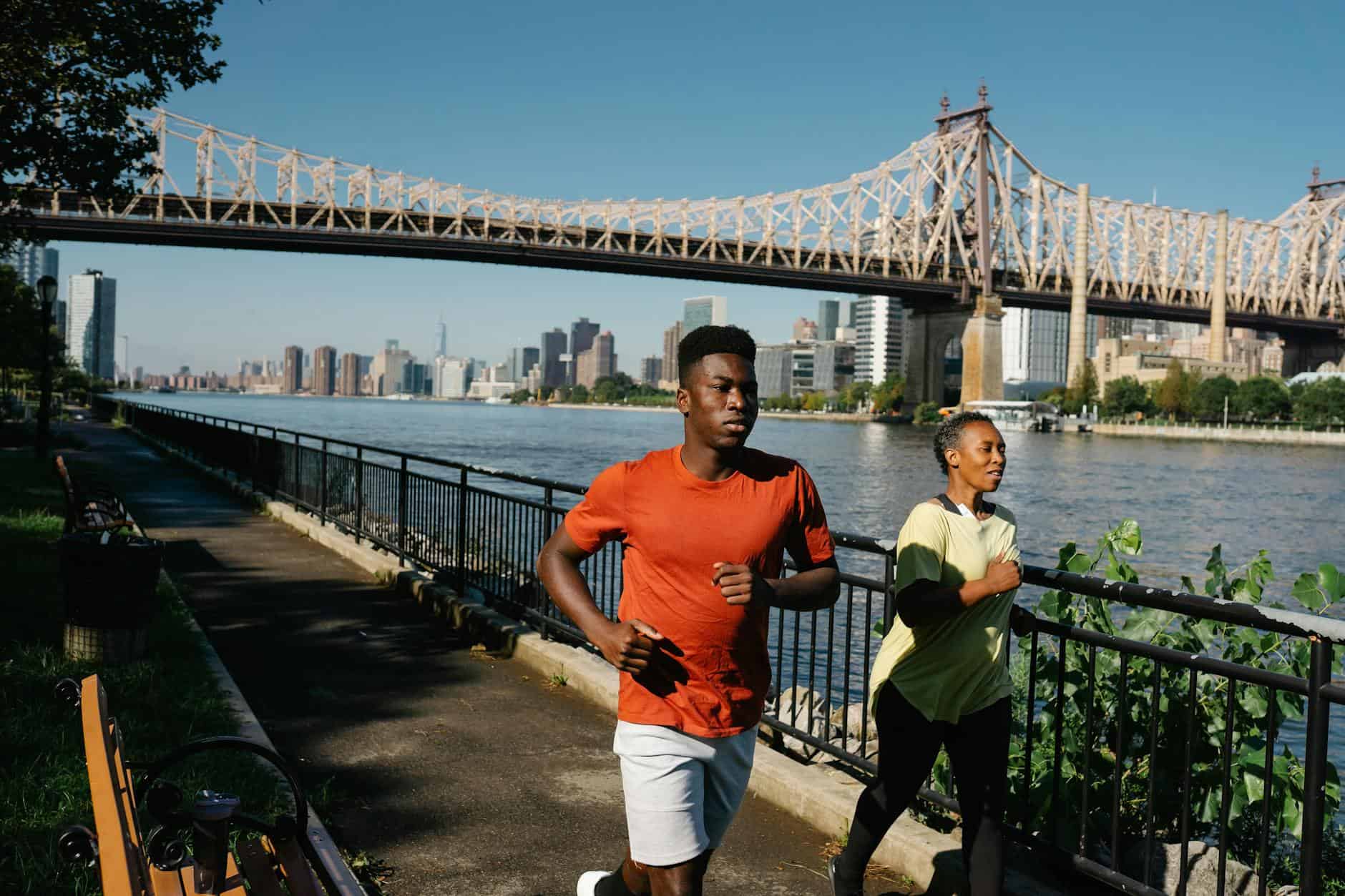 couple in sportswear running near bridge
